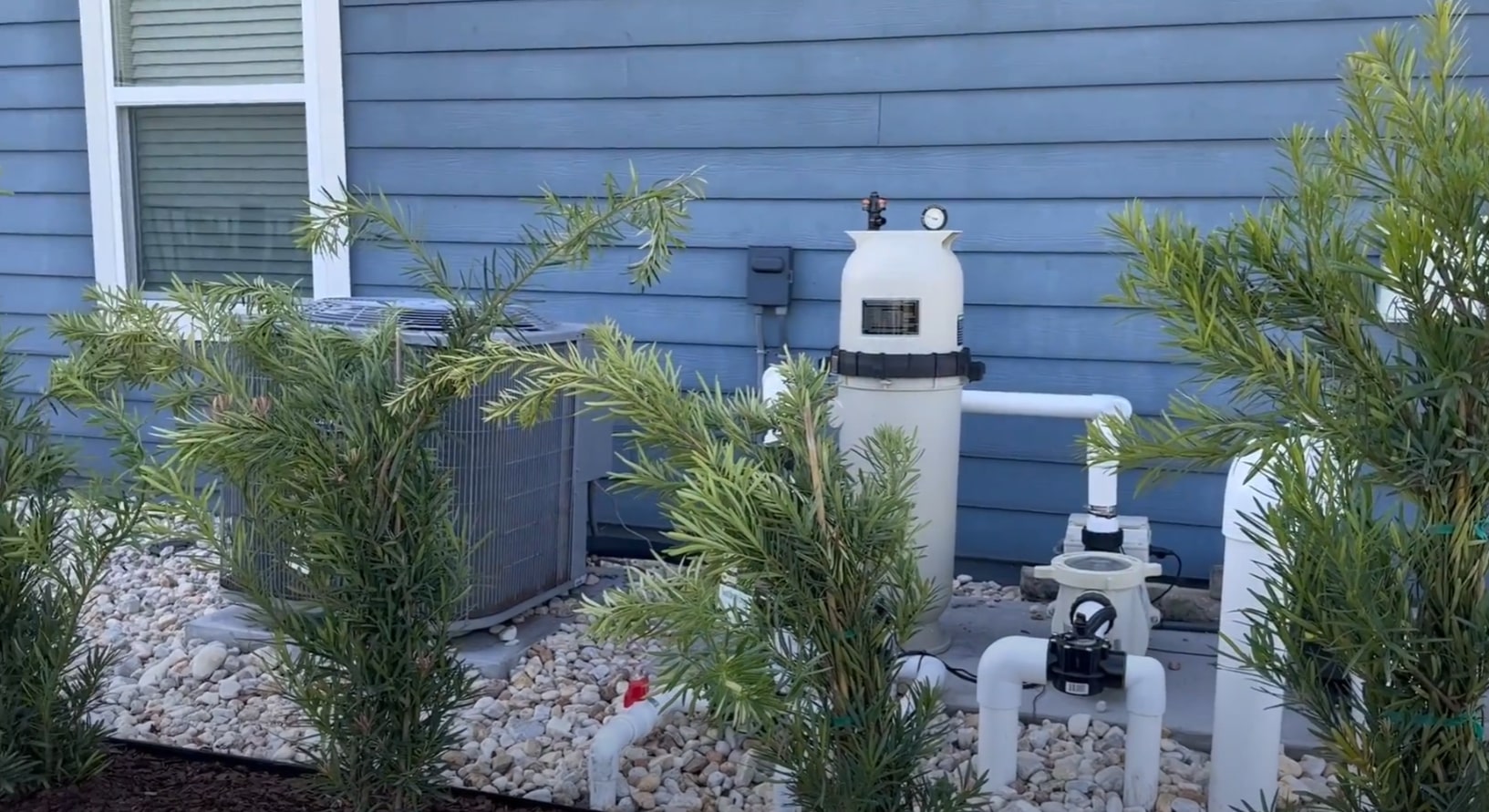 Professional pool equipment and landscaping installation with decorative rock elements and tropical plants